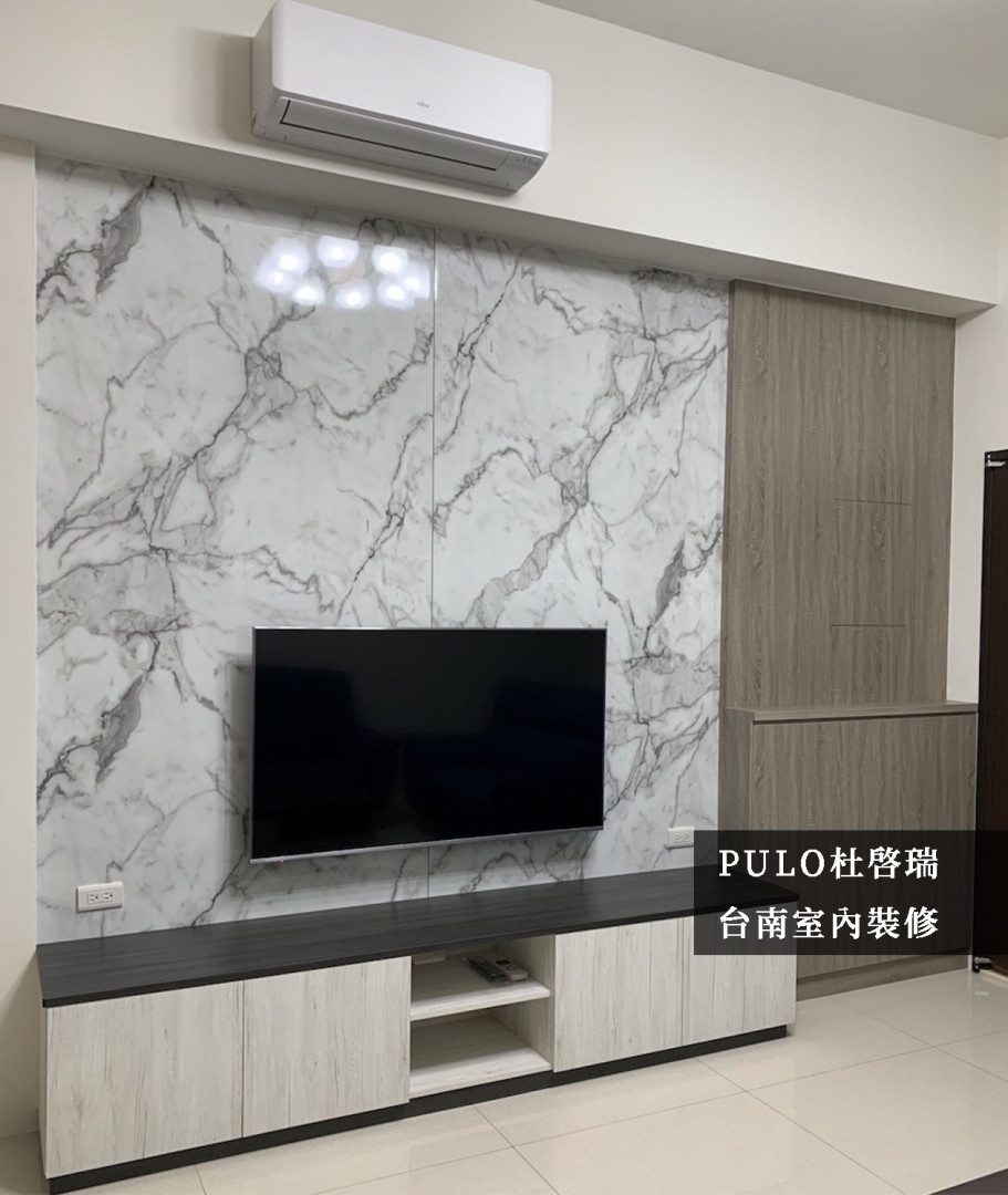 利用仿大理石的板材作為客廳主牆風格，下方的電視櫃的寬度也與電視牆切齊，讓空間的視覺效果更加整齊。牆面旁的櫃體深度是為了配合牆面的寬度，將客廳的畸零空間利用得淋漓盡致，顏色上則採用不同色調，來劃分明確的空間範圍。-PULO裝潢平台